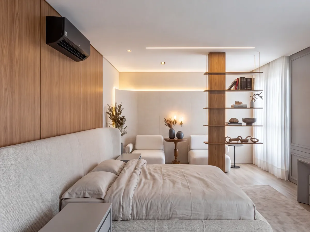 Suíte com painel de madeira, iluminação quente indireta, estante vazada e luz natural filtrada pela cortina